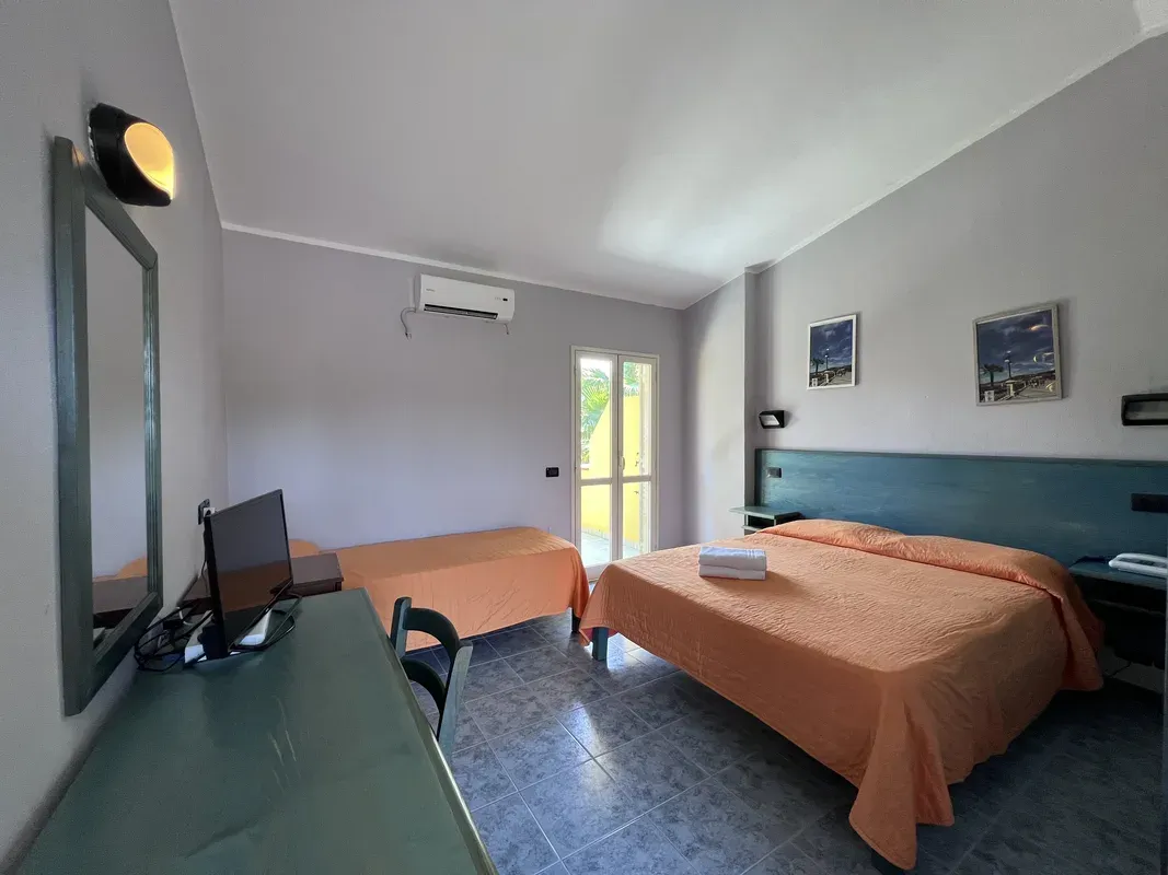 Camera con letto matrimoniale e singolo, copriletto arancione, TV e aria condizionata