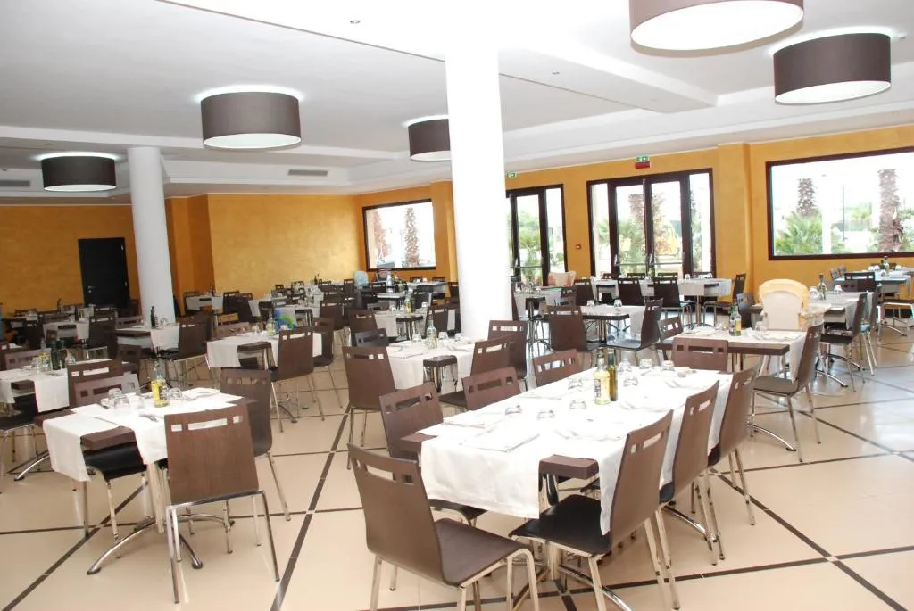 Sala ristorante interna con tavoli apparecchiati, sedie scure e ampie vetrate