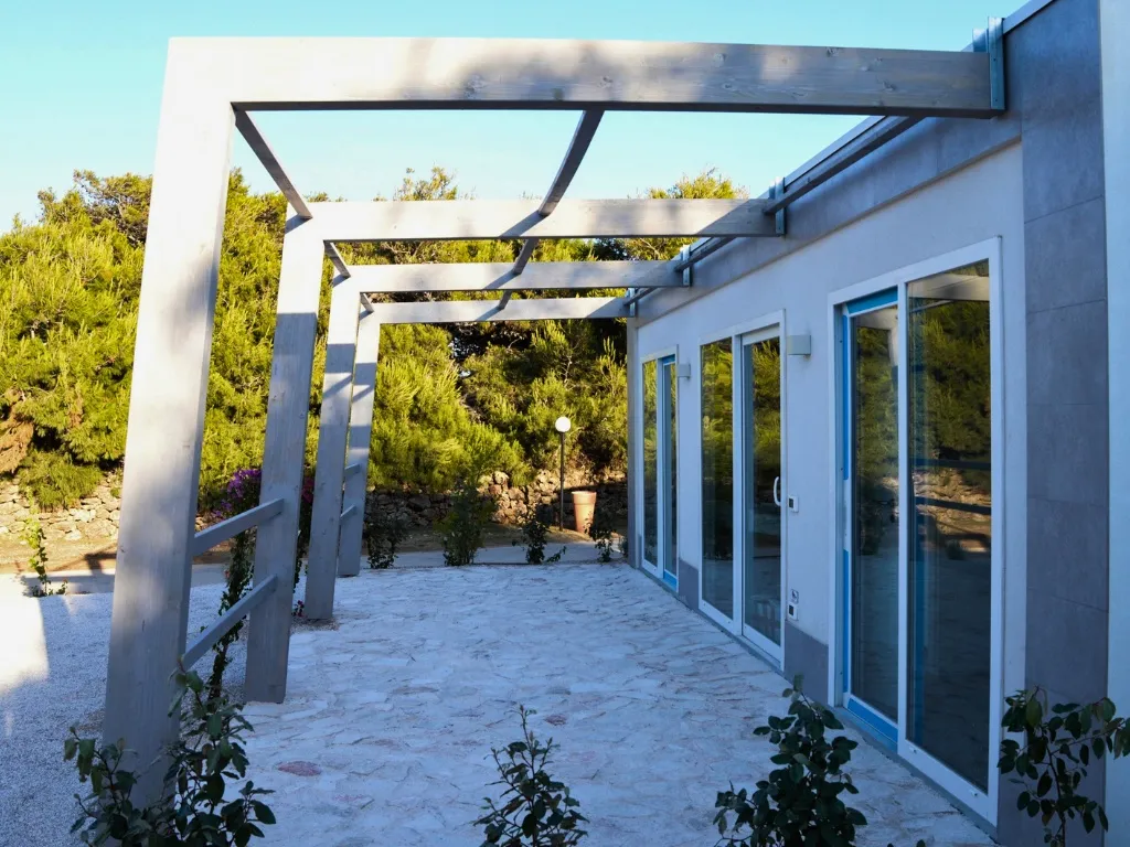 Terrazza esterna con pergolato in legno e vetrate immersa nel verde